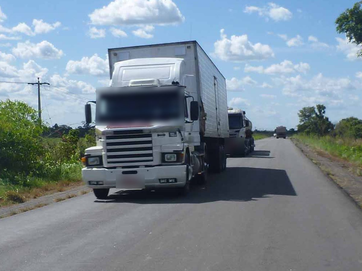 Caminhão-baú chegando pela rodovia, identificado pela carroceria