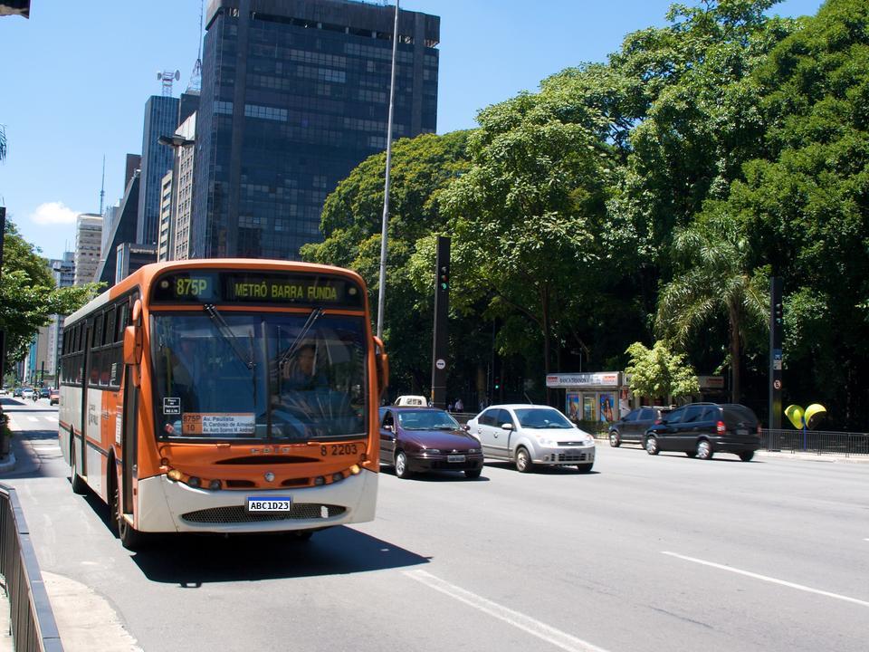 Ônibus na faixa exclusiva de uma avenida, com carros na faixa ao lado