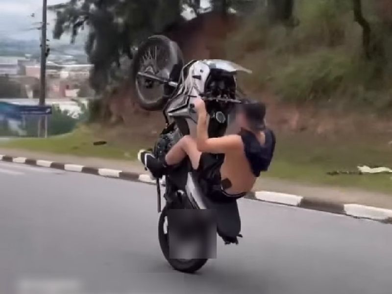 Motociclista empinando a moto em via urbana